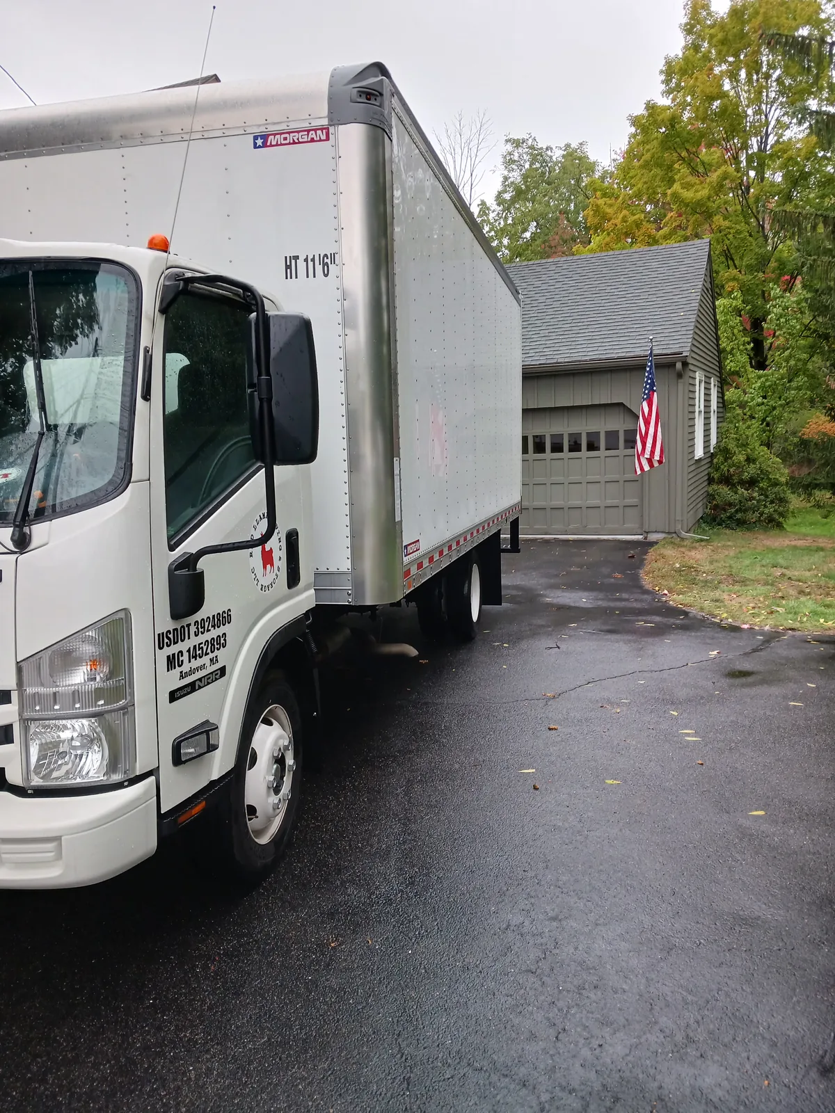 Red Llama moving truck in an autumn residential driveway.