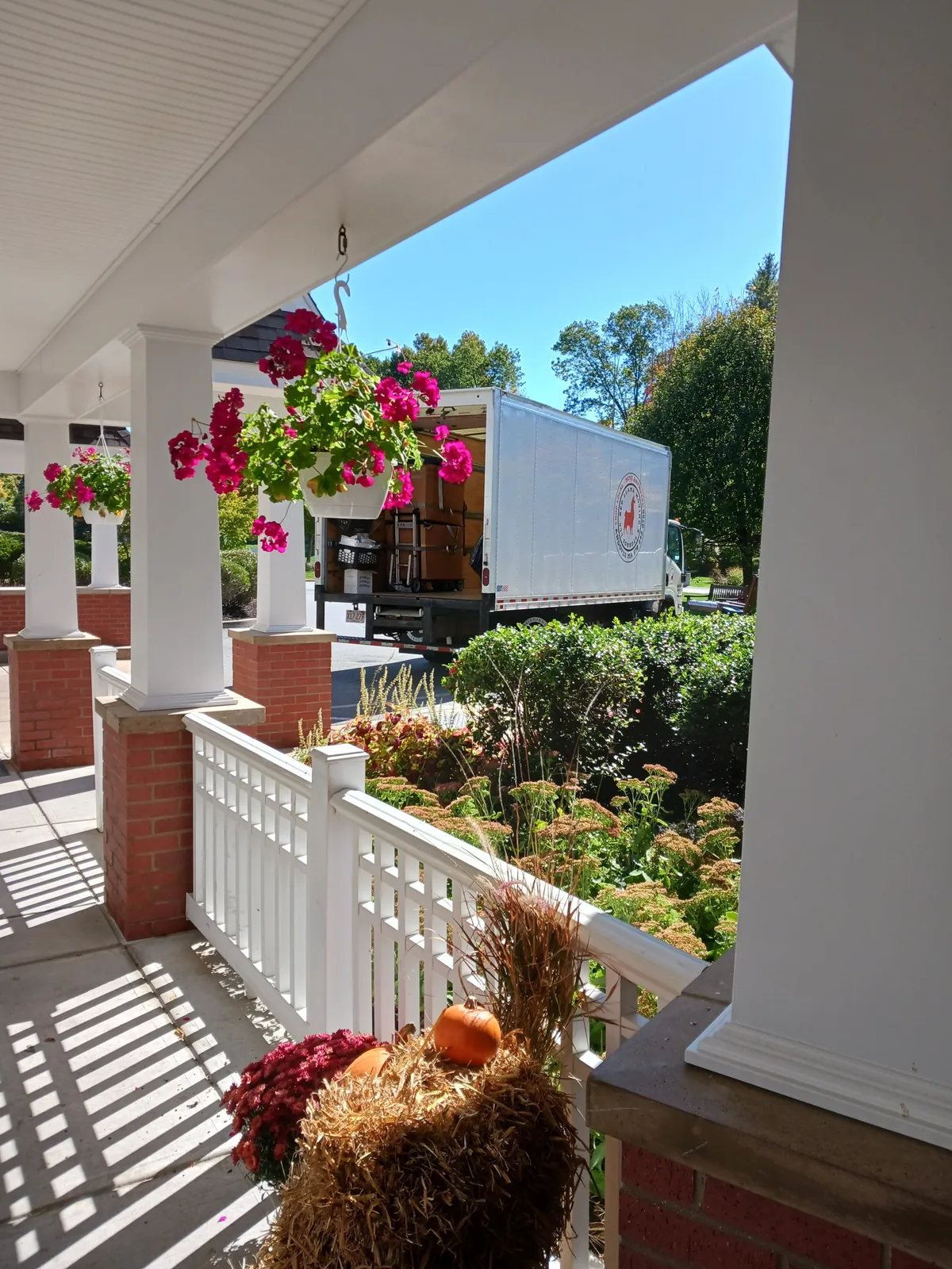 Red Llama moving truck with its cargo door open beside a residential porch.